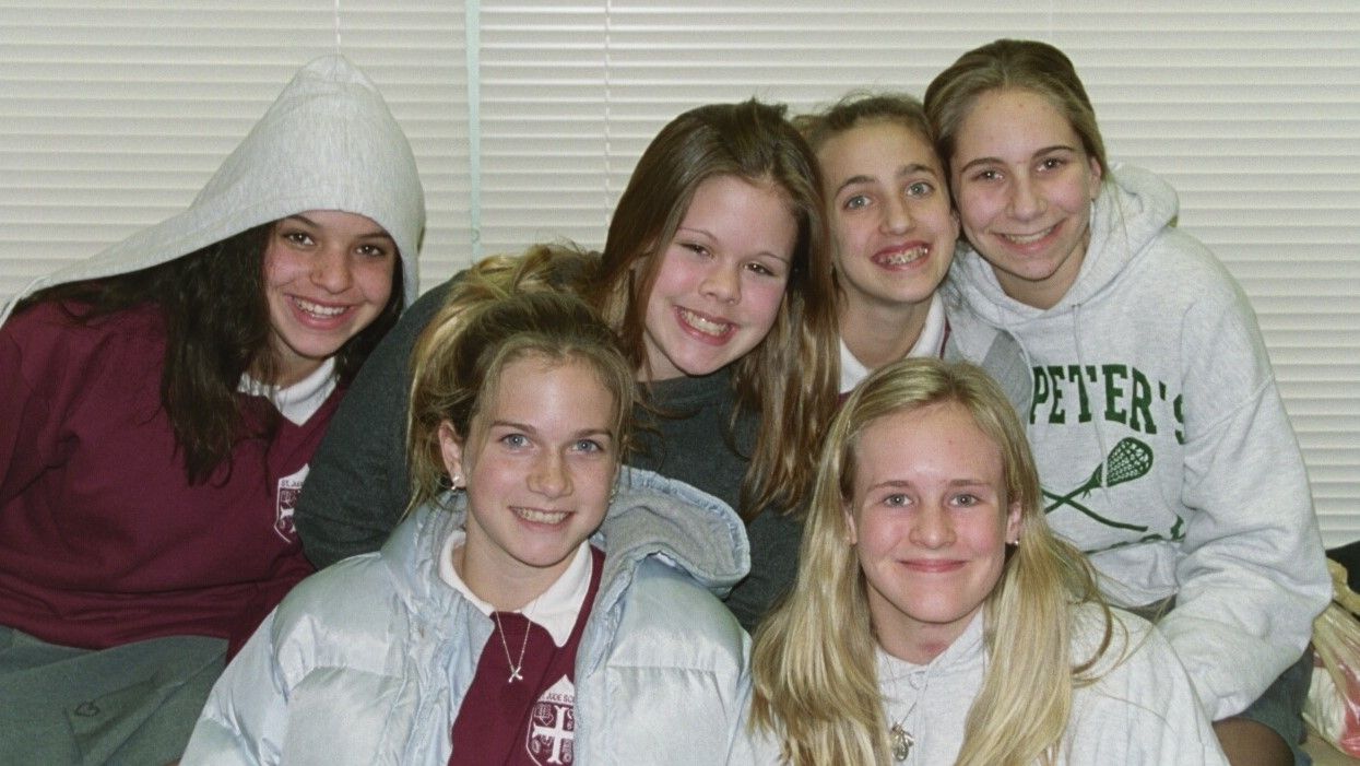 Five smiling friends posing together on a couch indoors
