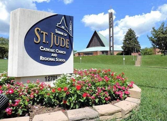 St. Jude Catholic Grade School sign with flowers and church building on a sunny day