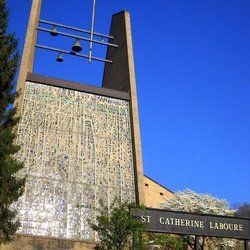 St. Catherine Labouré church facade with bell tower against a bright blue sky.