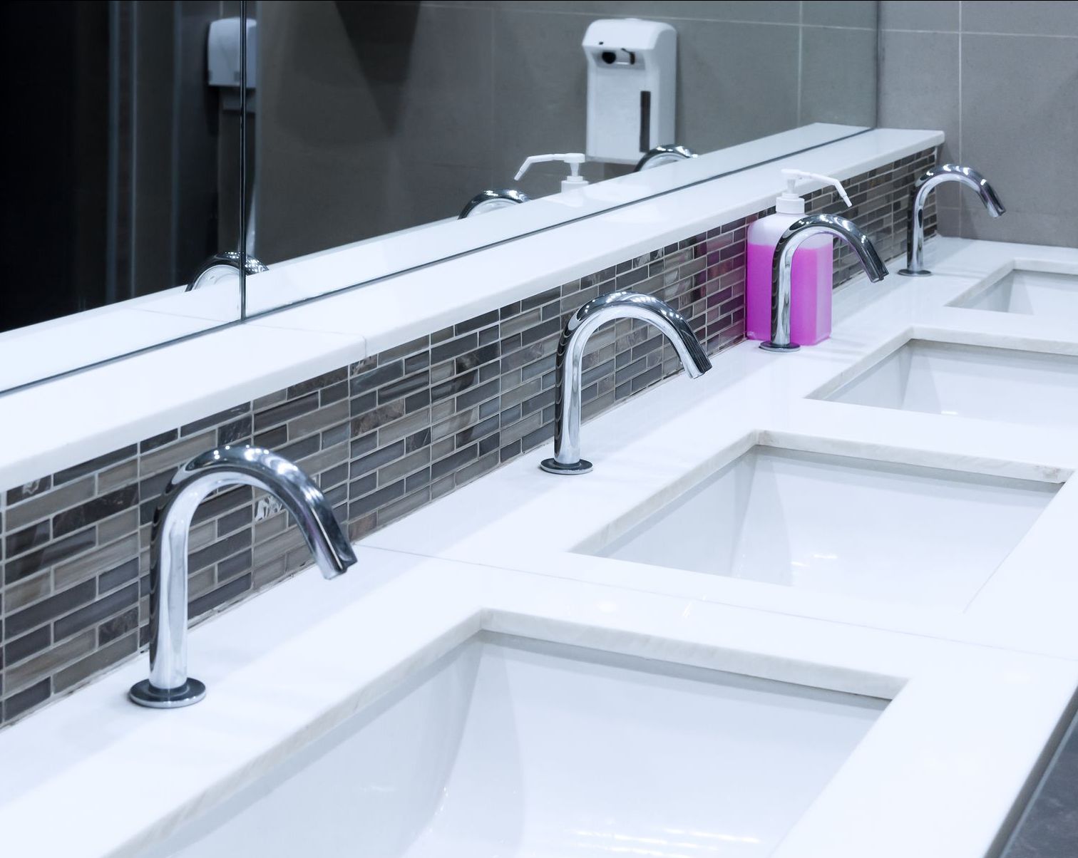 Une salle de bain avec trois lavabos et un miroir