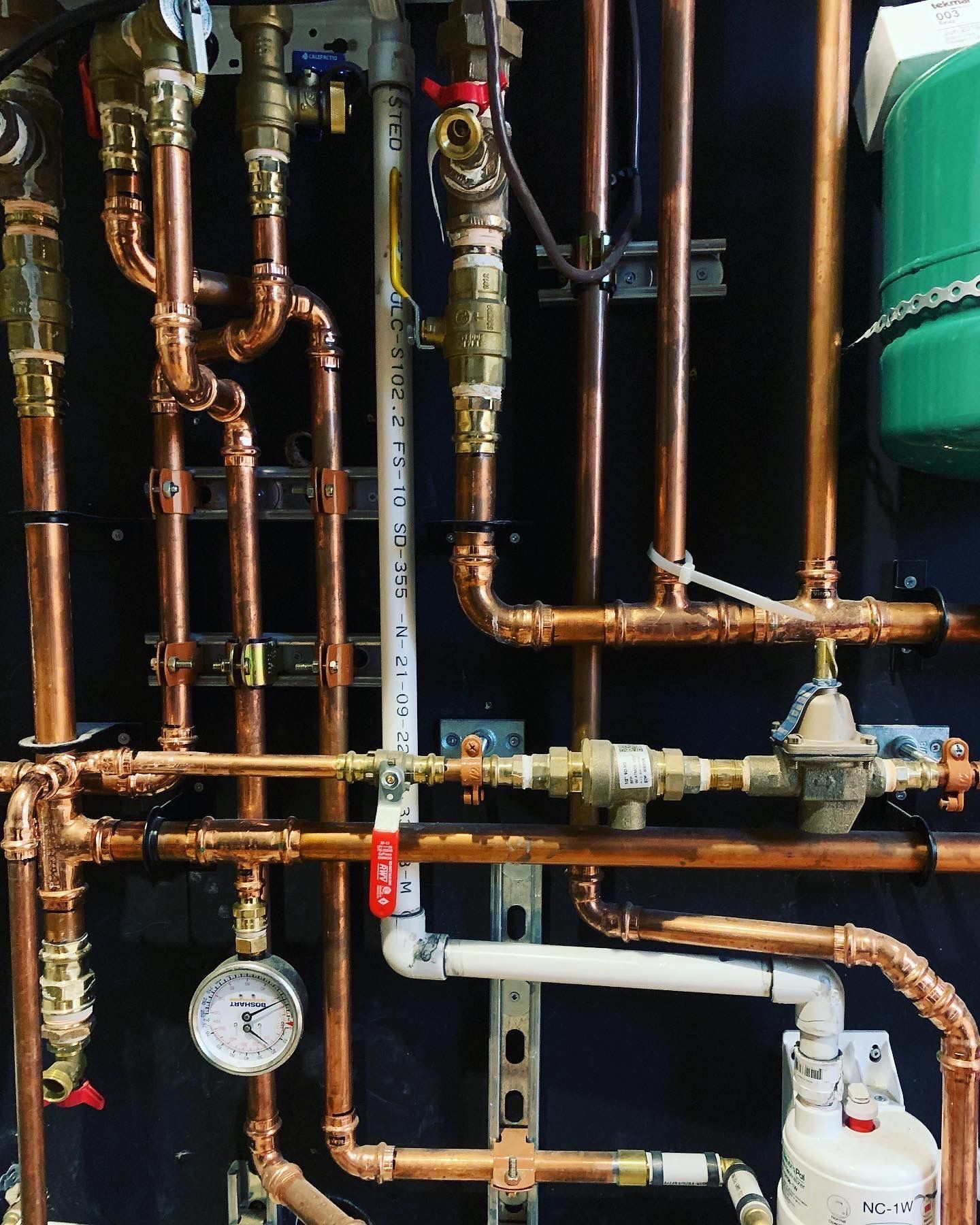A bunch of copper pipes are connected to a green tank