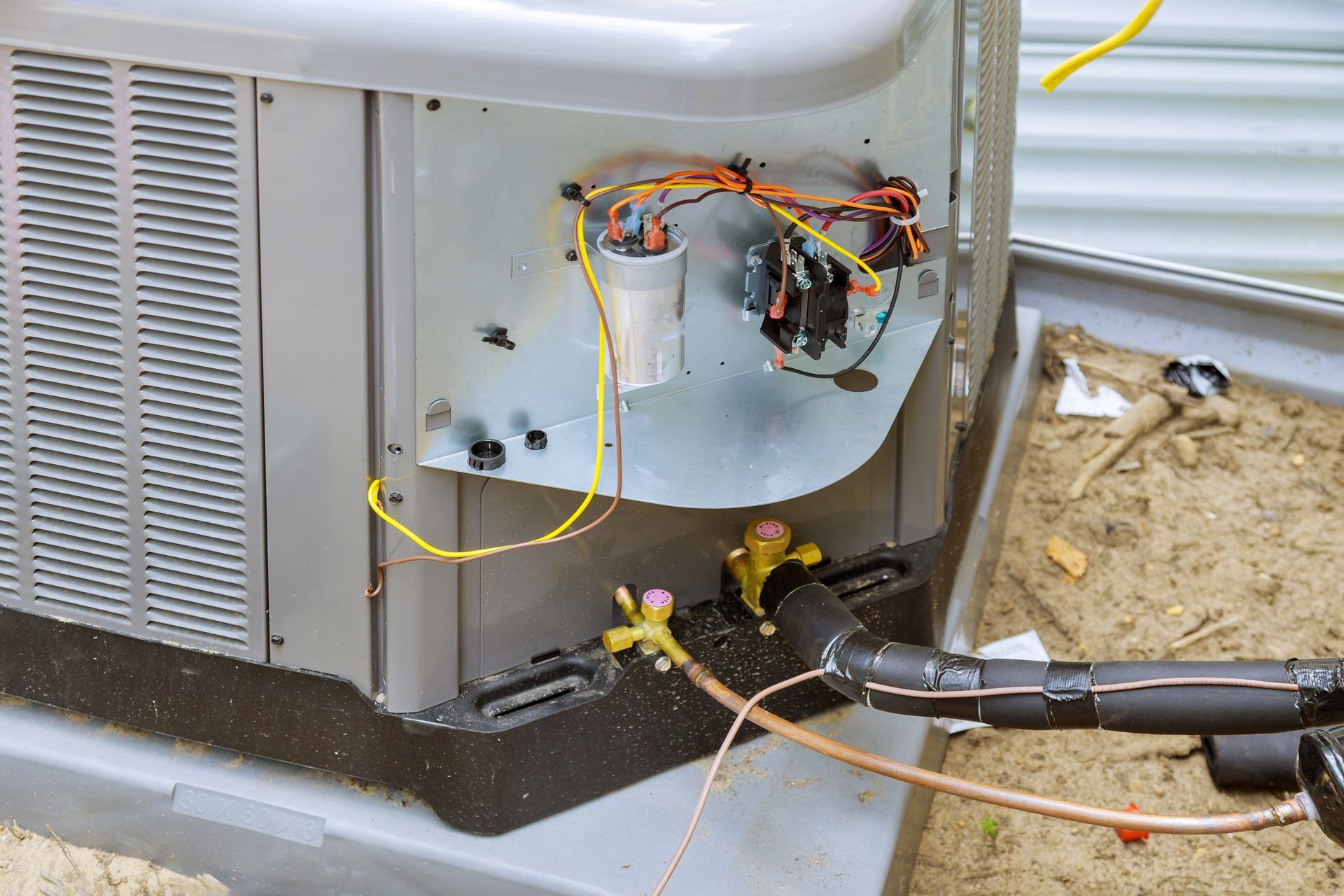 Technician using a torch to repair exposed wiring on an outdoor HVAC unit