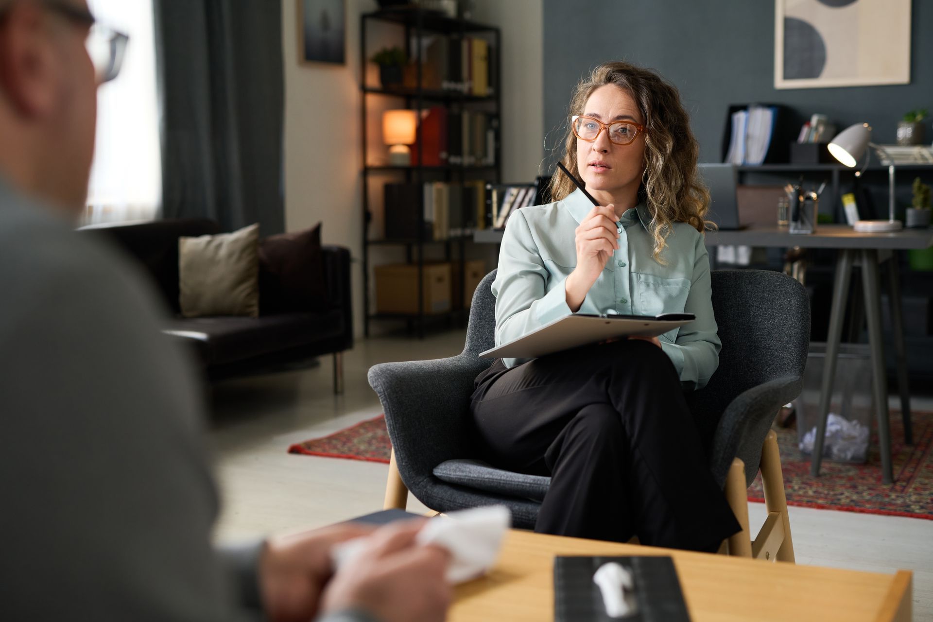 A woman is sitting in a chair talking to a man.