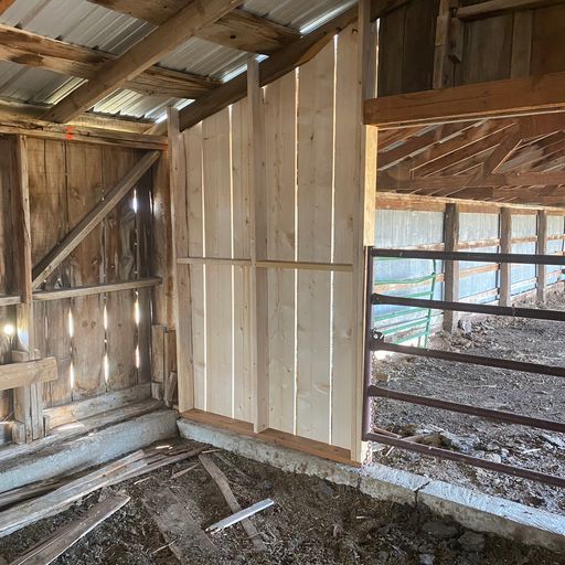 The inside of a wooden barn with a metal fence.