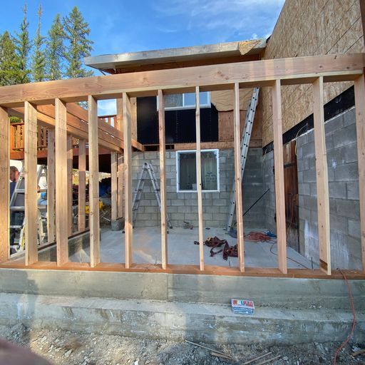 A house is being built with wooden beams and a ladder.