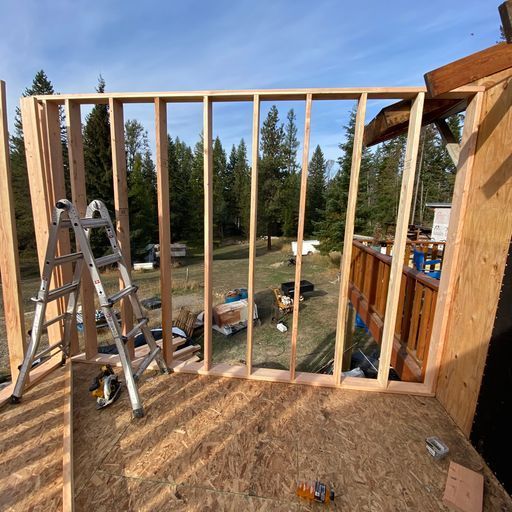 A ladder is sitting in front of a wooden wall that is being built.