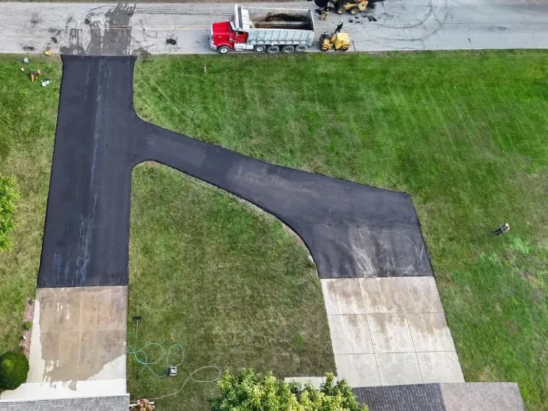Aerial view of a driveway and lawn with a truck parked along the road.