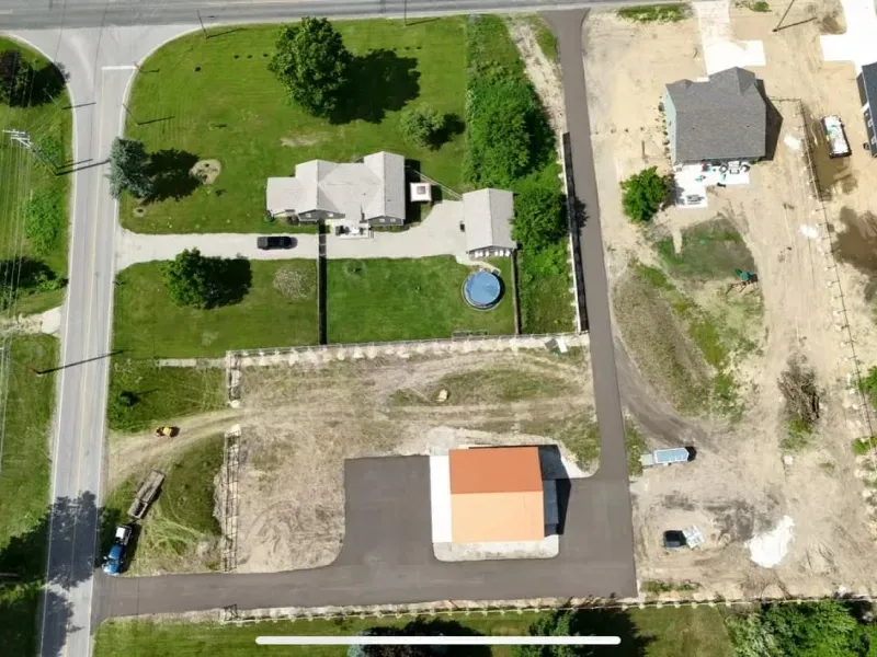 Aerial view of two houses with lawns, driveways, and adjacent construction site.