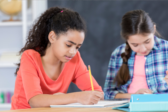 2 middle school girls at a table doing schoolwork