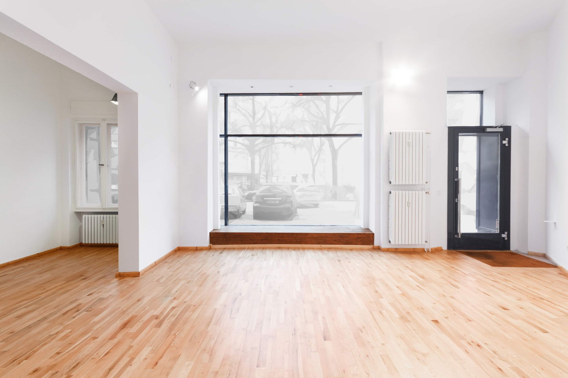 An empty room with hardwood floors and a large window.