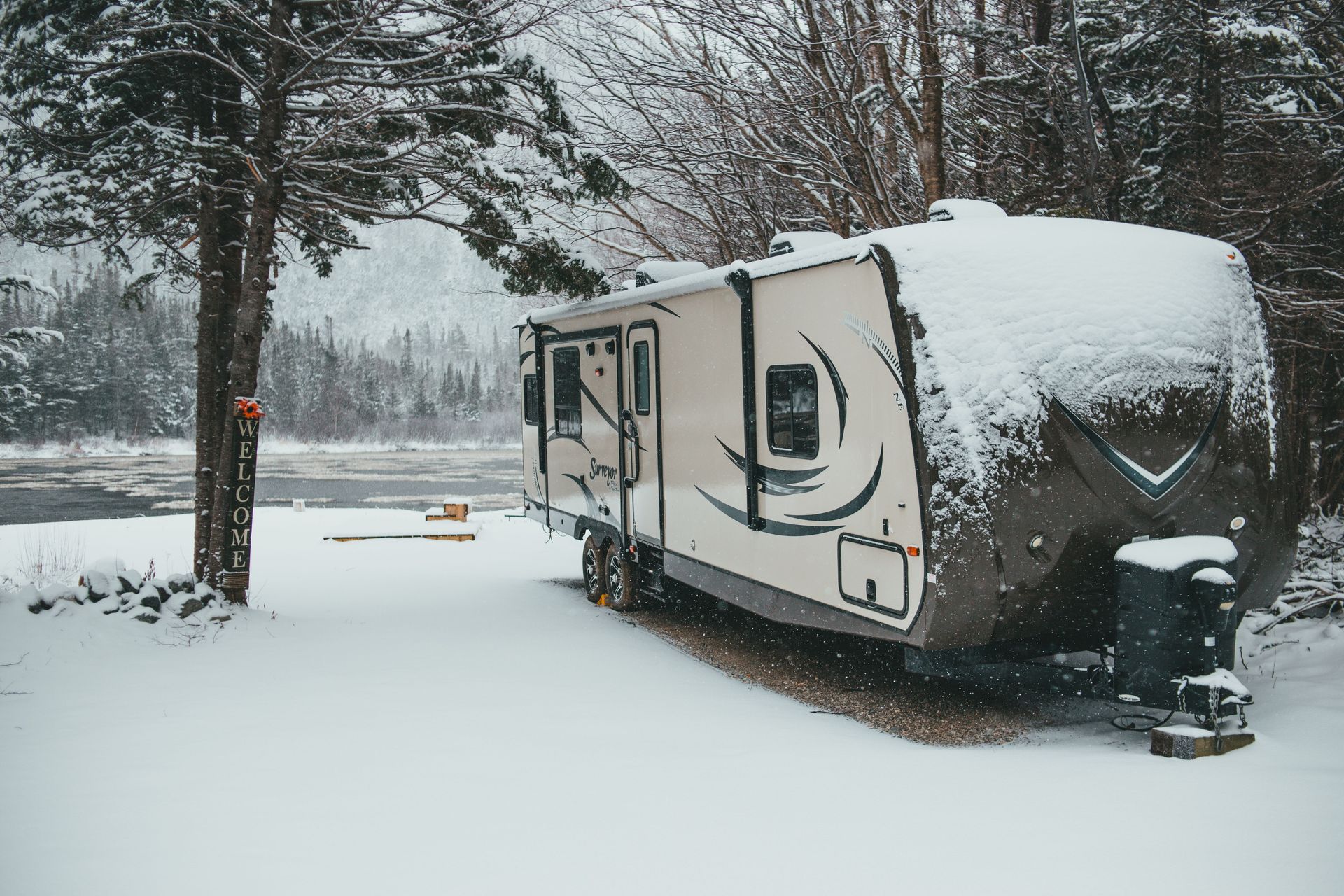 Snow-covered RV parked in a snowy campsite with trees in the background
