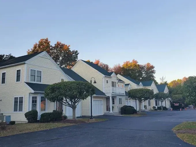 A row of white houses with green roofs are lined up on a street.