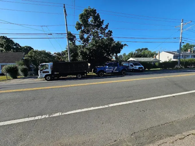 A black truck is parked on the side of the road next to a blue truck.