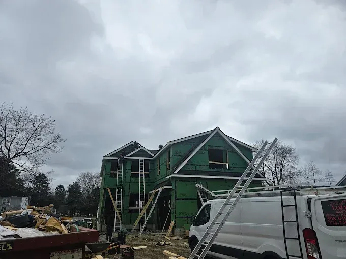 A white van is parked in front of a house under construction.