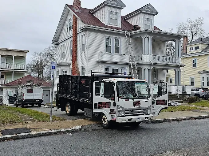 A dump truck is parked in front of a large white house.