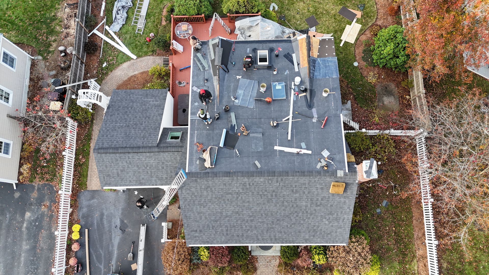 Aerial view of construction workers installing a flat roof on a house during a renovation project.