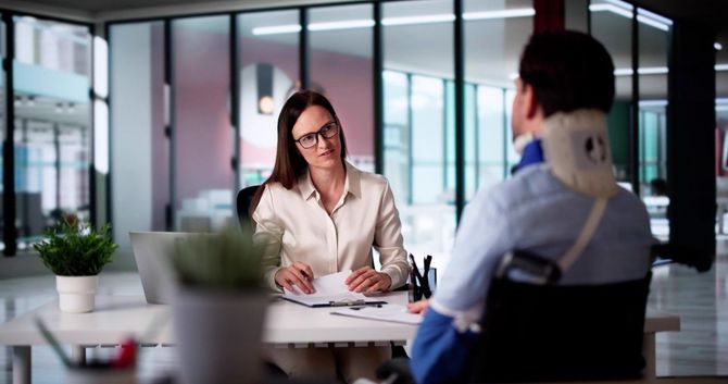 Two people meeting across a table in a modern office, discussing documents during a consultation.
