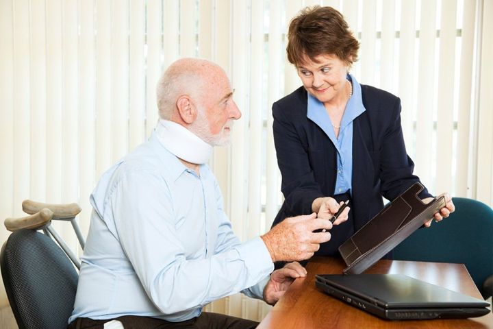 Two coworkers discussing a tablet at a desk in a bright office