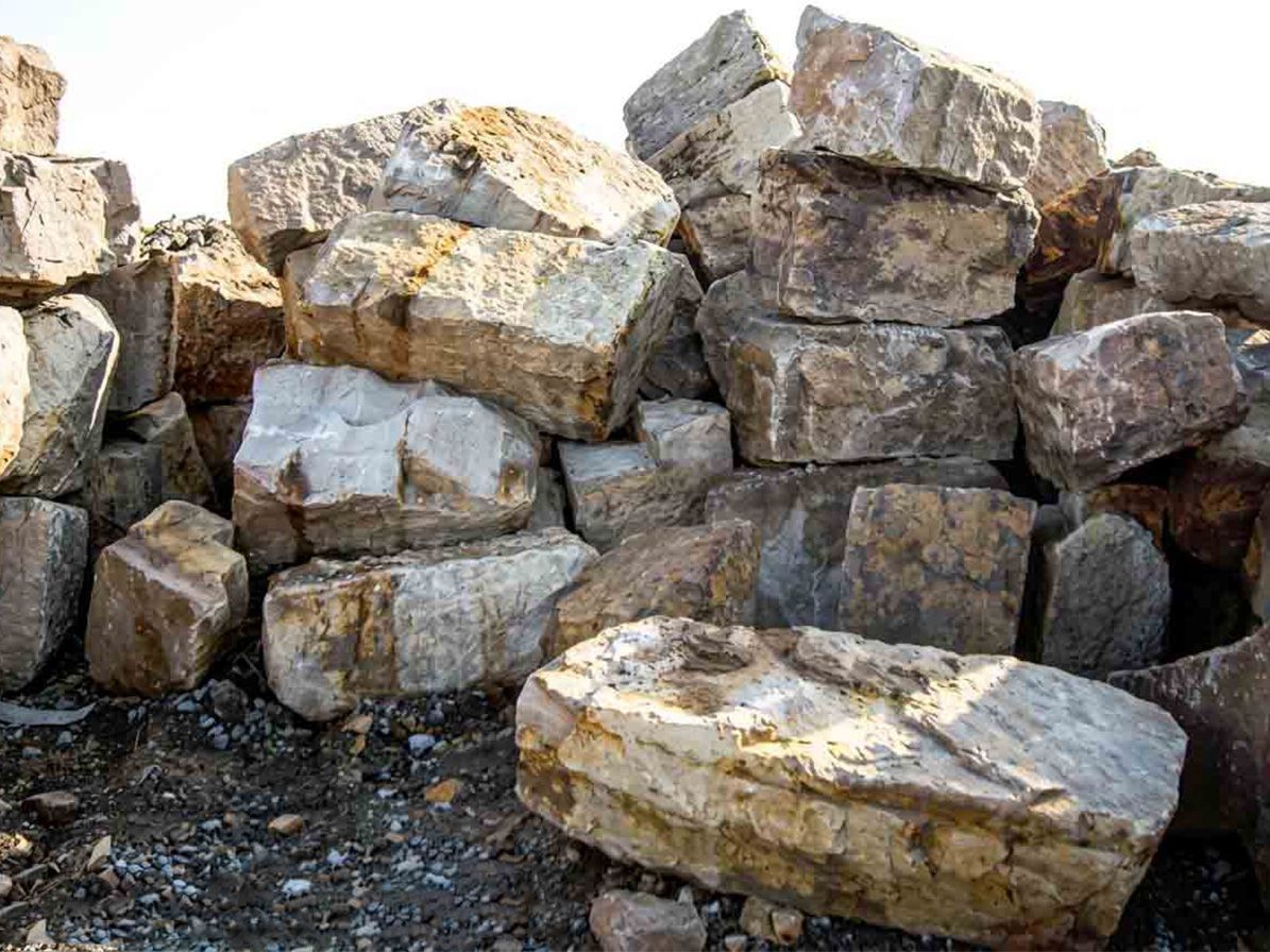 Pile de gros blocs de pierre brute empilés en plein air sur du gravier