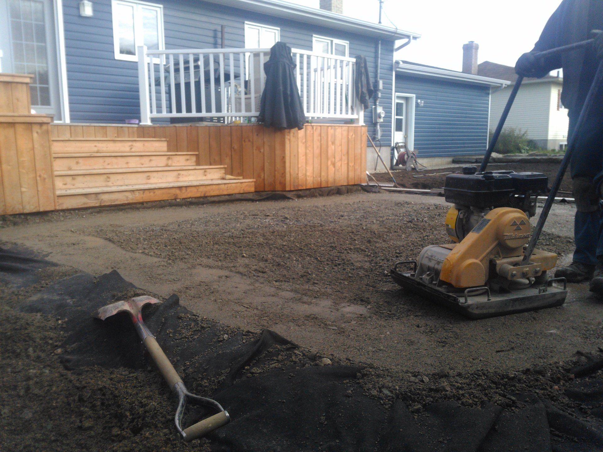 Un homme utilise une machine pour niveler le sol devant une maison
