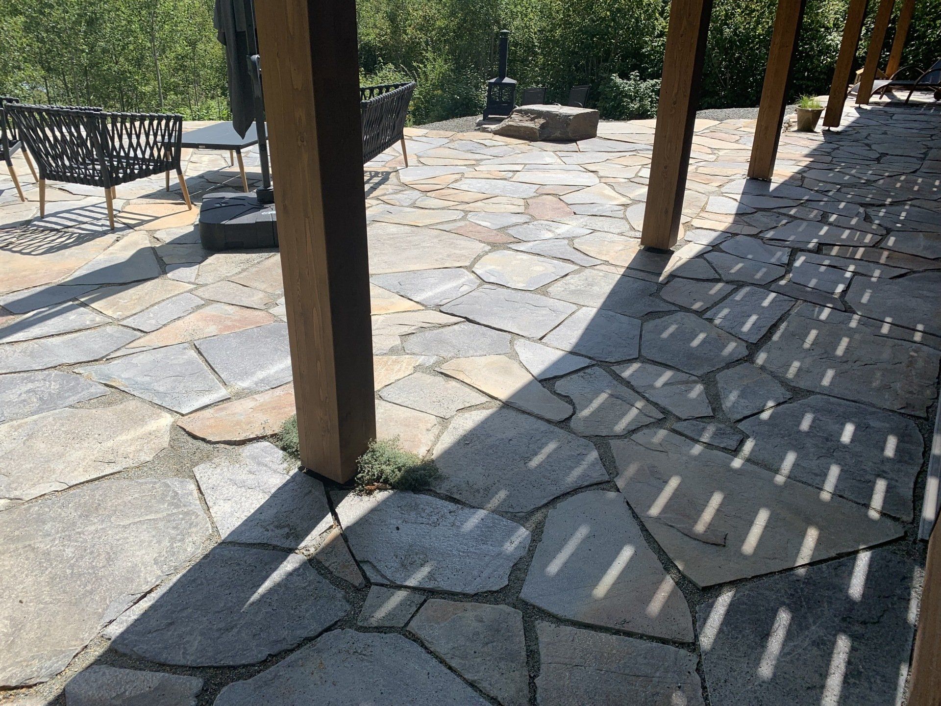 Une terrasse en pierre avec banc et chaises sous pergola.