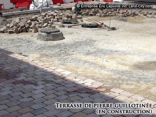 Terrasse de pierre guillotinee en construction est inscrite au sol