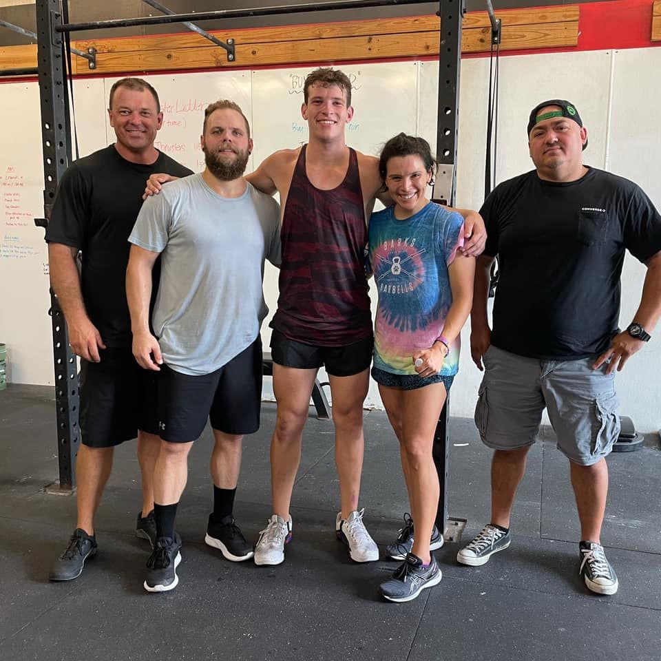 Five people posing in a gym; diverse body types and clothing.
