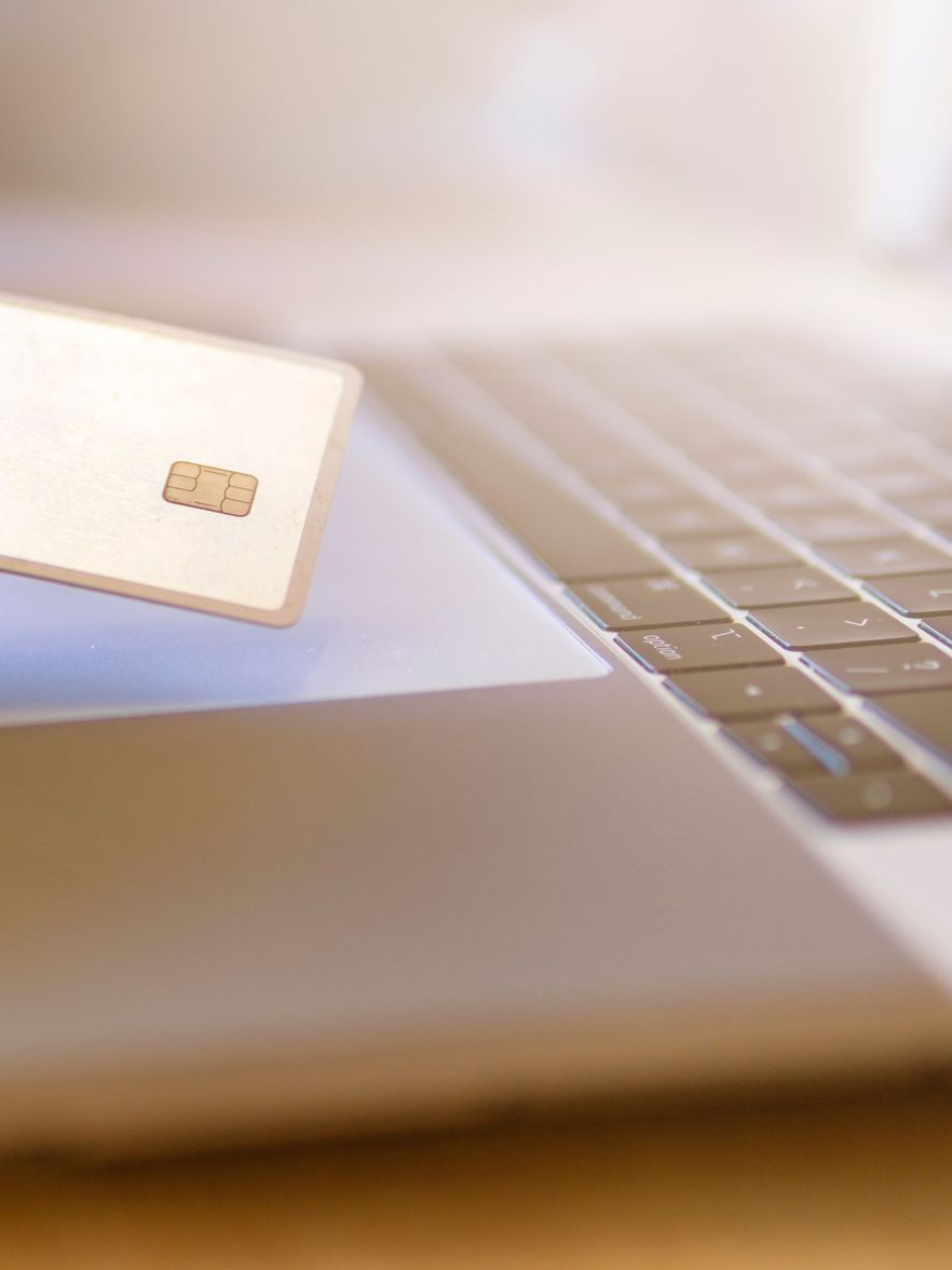 Close-up of a credit card being inserted into a laptop’s card reader slot