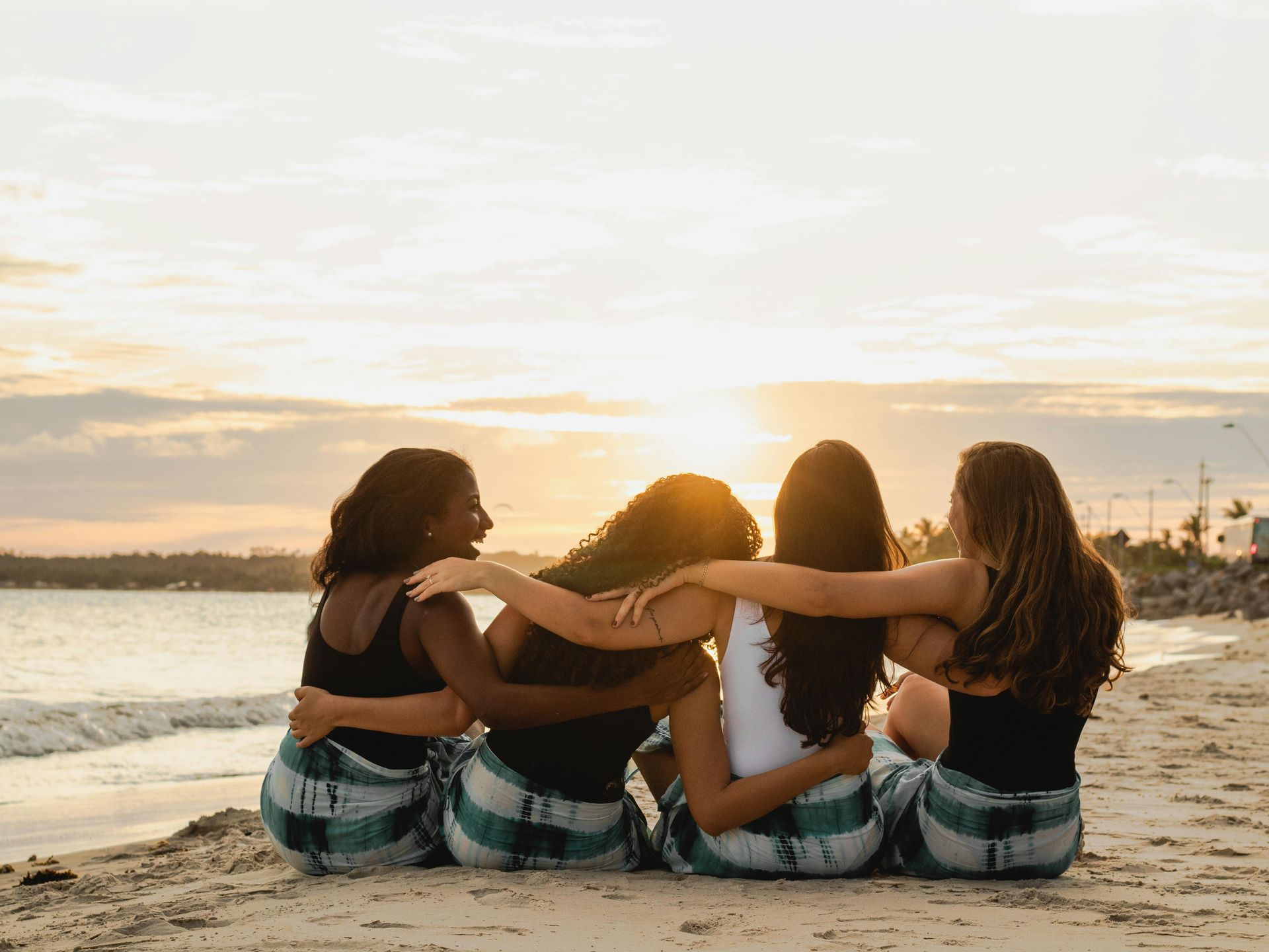 girls with their arms around each other at the beach