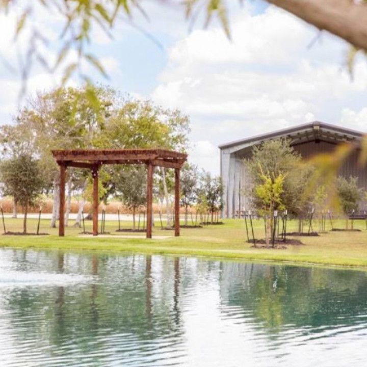 Wooden pergola and industrial building reflected in a pond on a sunny day.