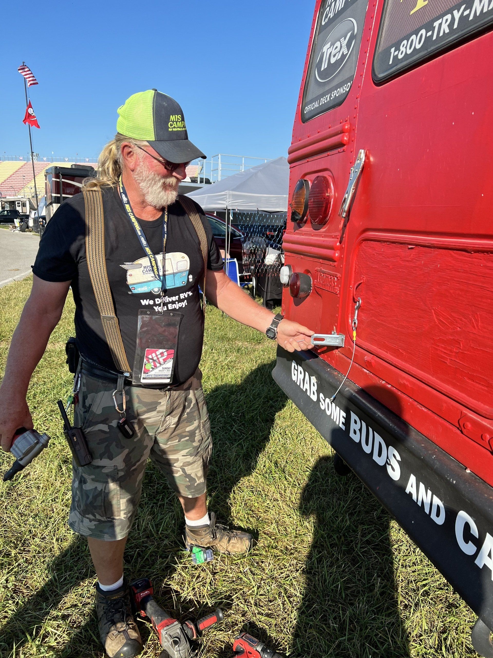 A man standing next to a red van that says grab some buds and ca