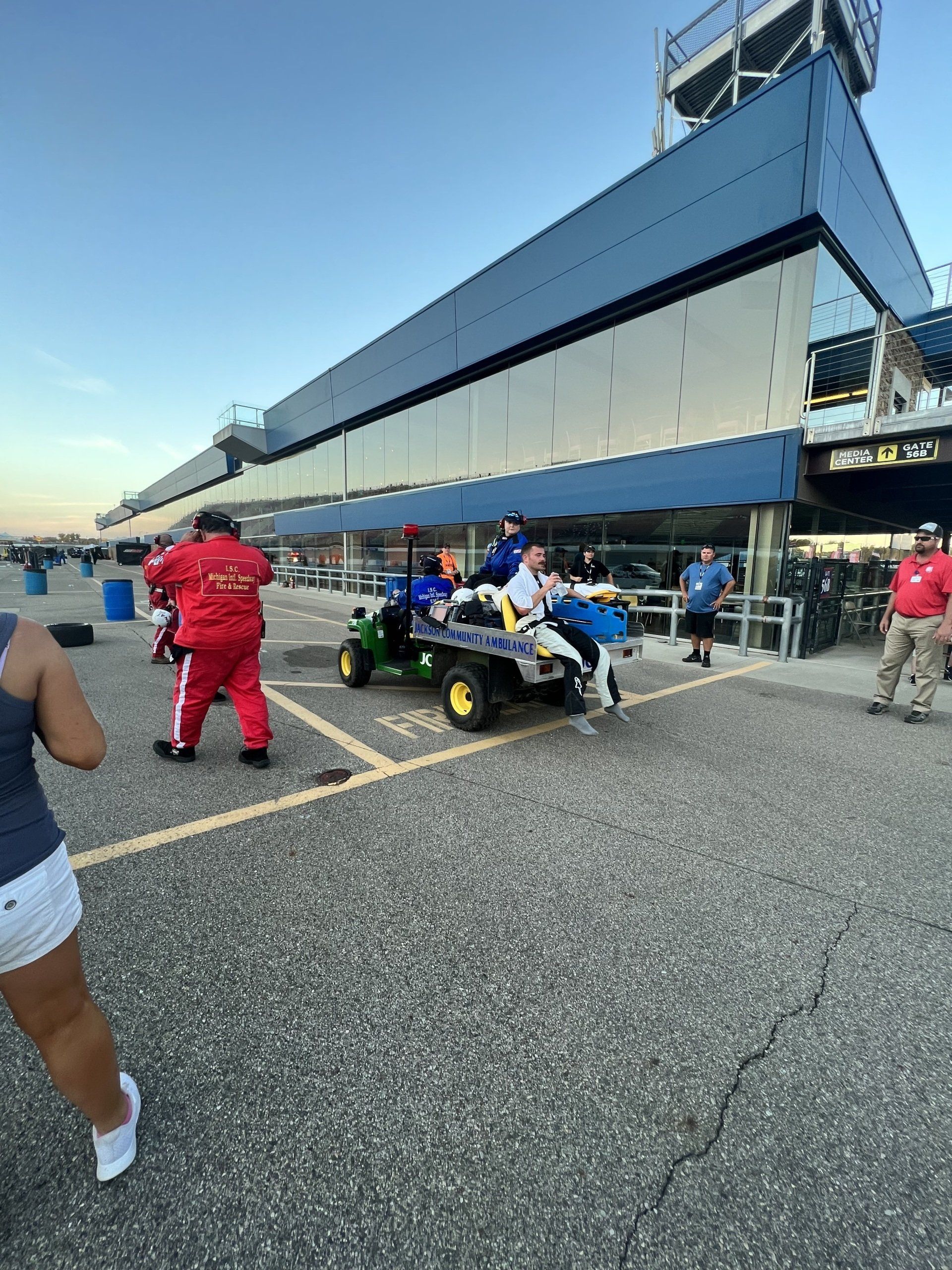 A group of people are standing around a lawn mower in a parking lot