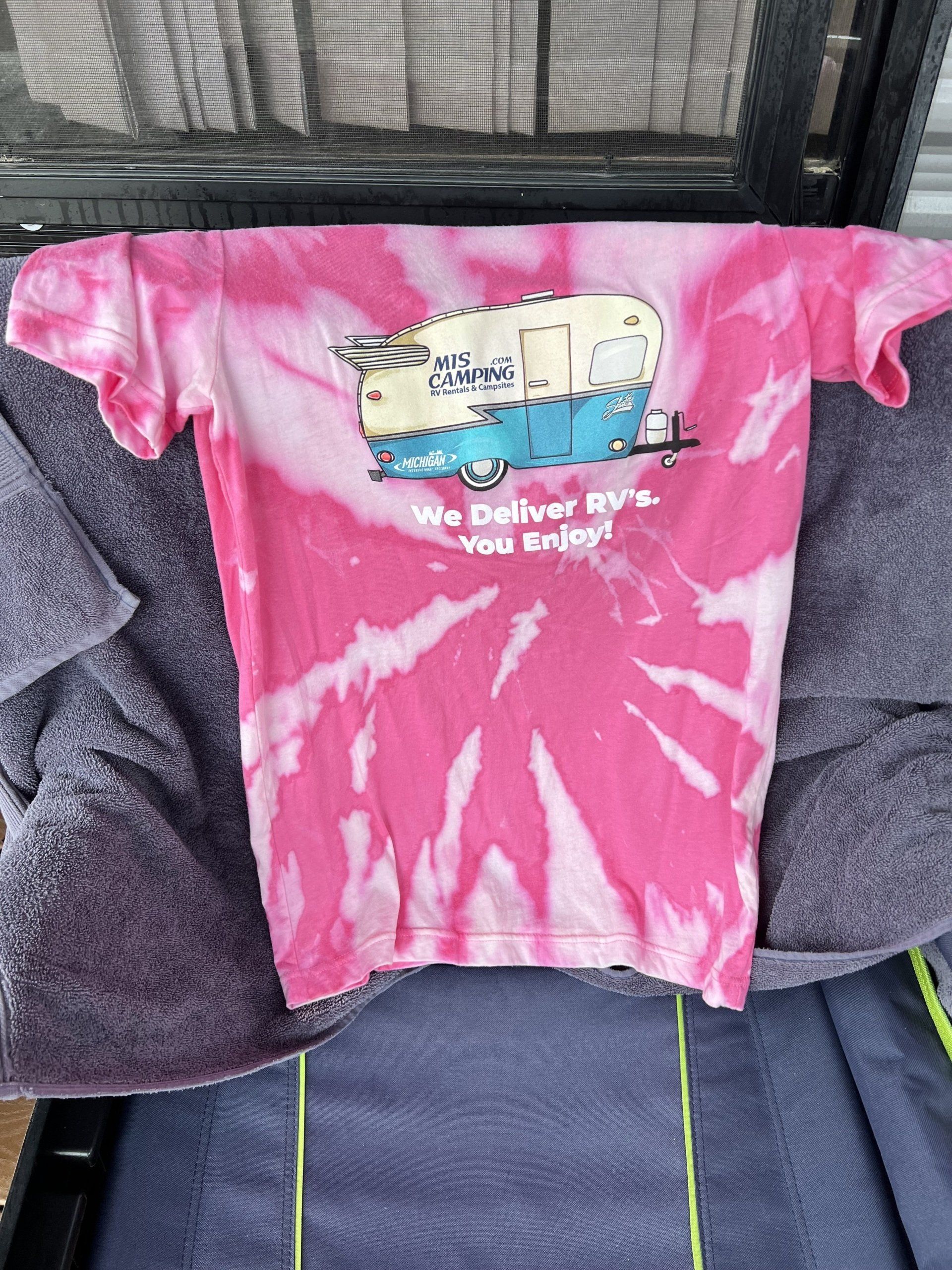 A pink tie dye t-shirt is hanging on a chair.