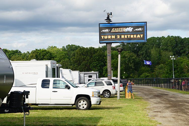A white truck is parked in front of a sign that says turn 2 retreat