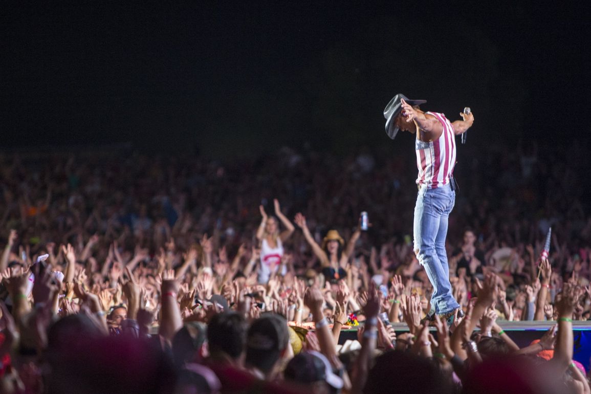 A man is standing on a stage in front of a crowd at a concert.