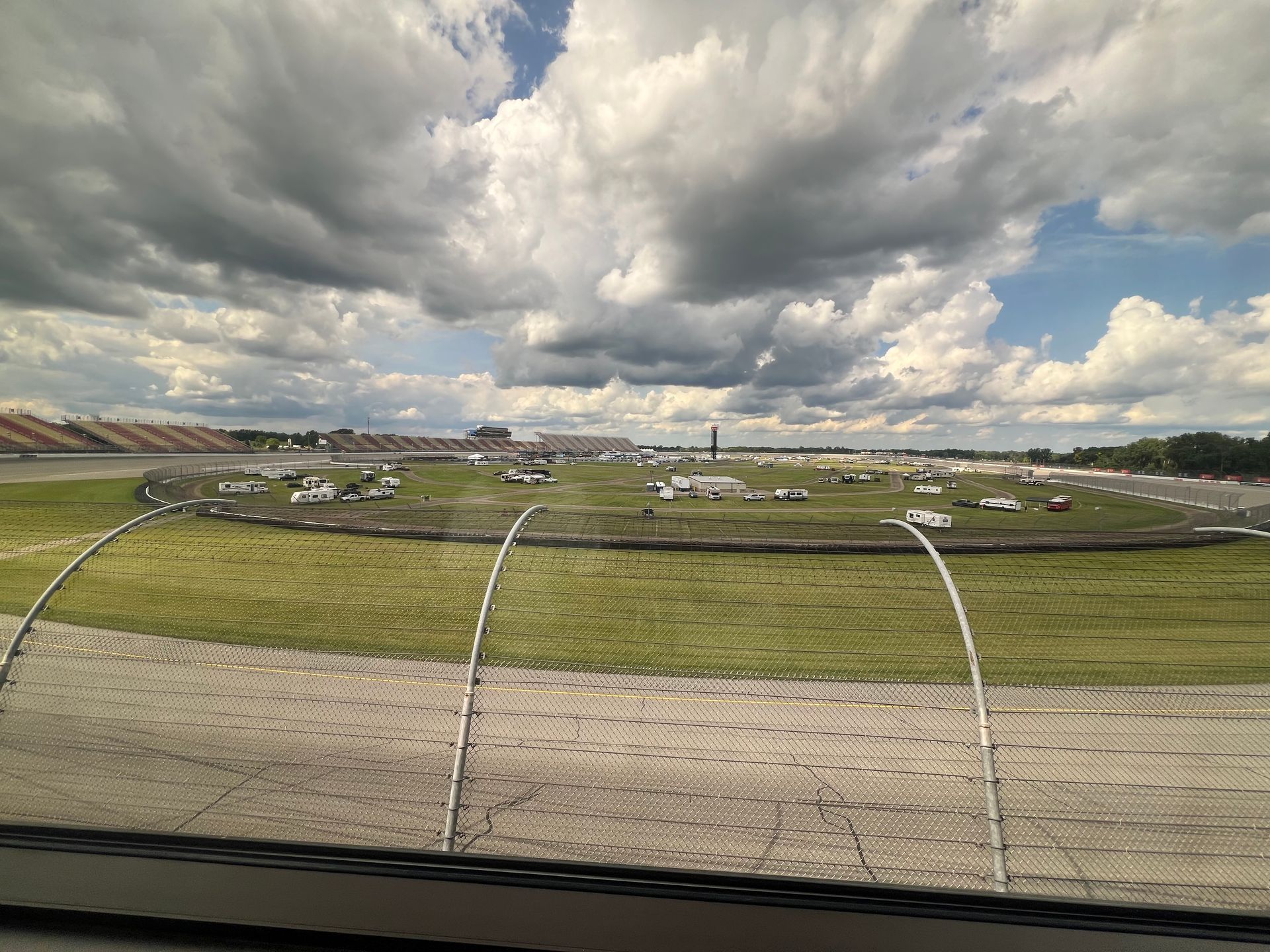 Race track under cloudy sky with infield, seen from a higher vantage point.