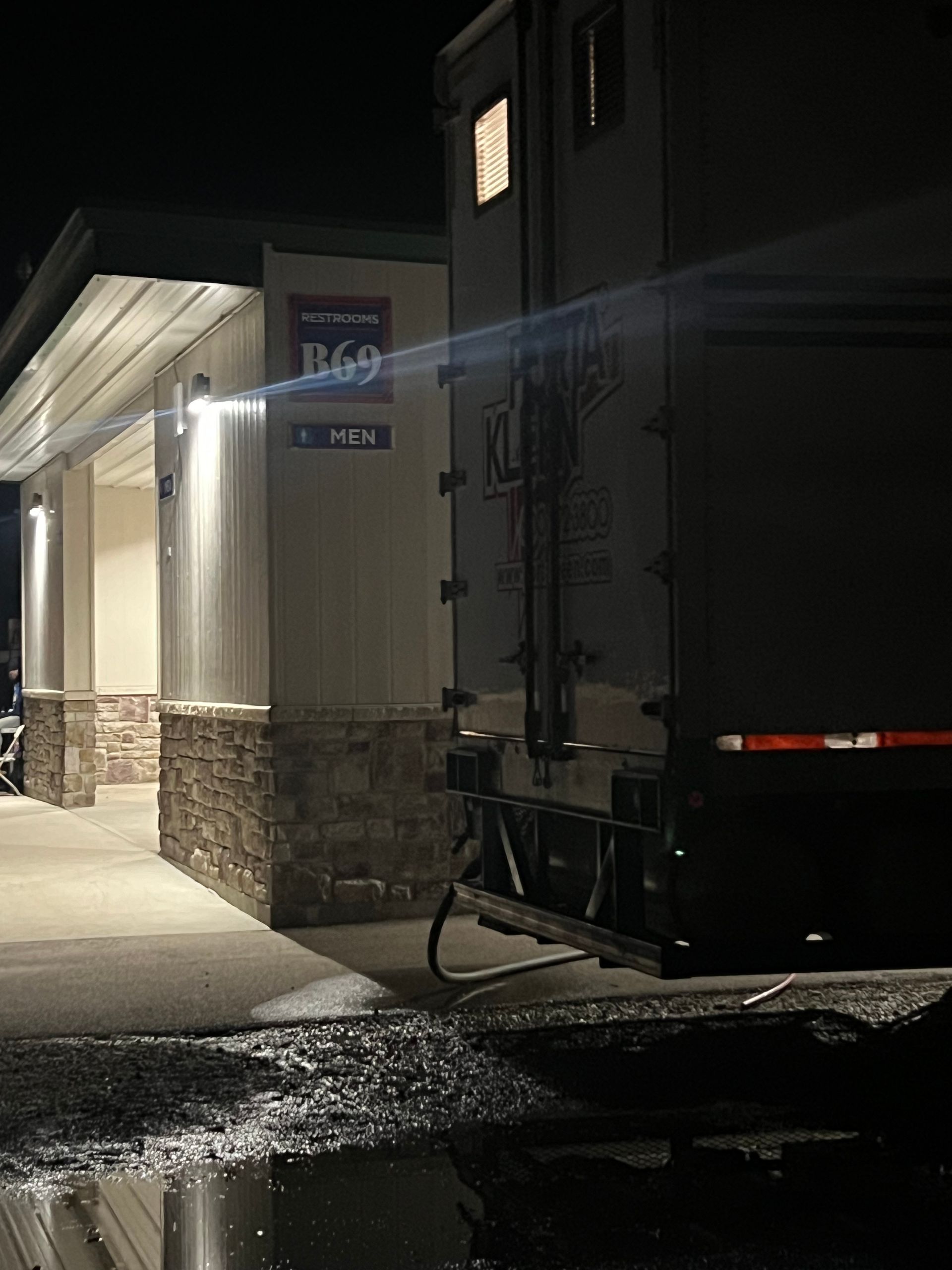 Truck backed up to a building at night; sign shows 