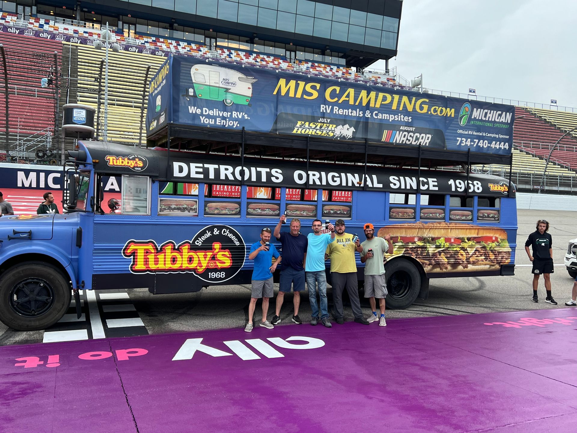 People pose in front of a blue school bus, decorated with 