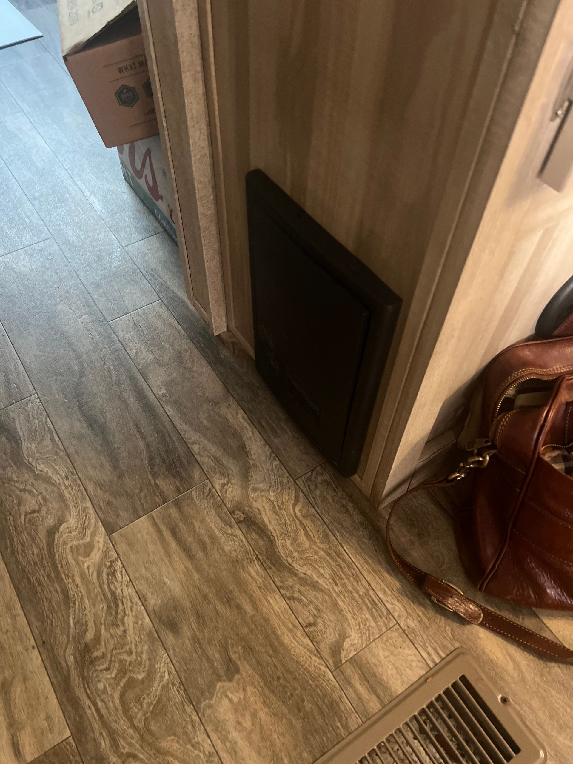 A dark rectangular panel on a beige wall in a room with wood-look flooring.