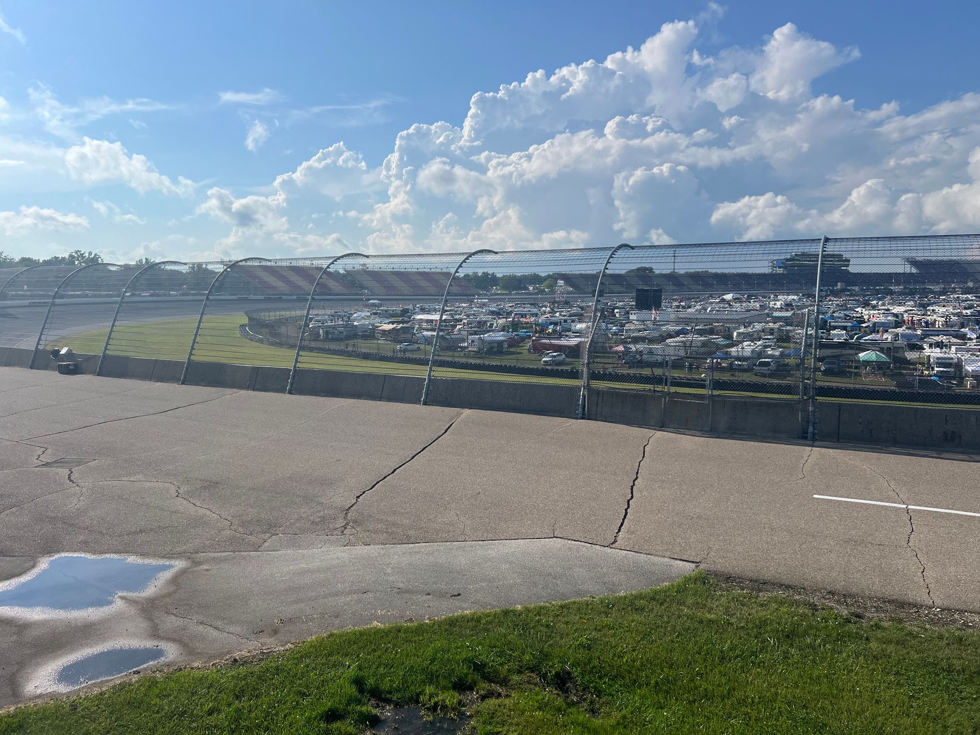 Race track with grandstands, parking, and a cloudy sky.