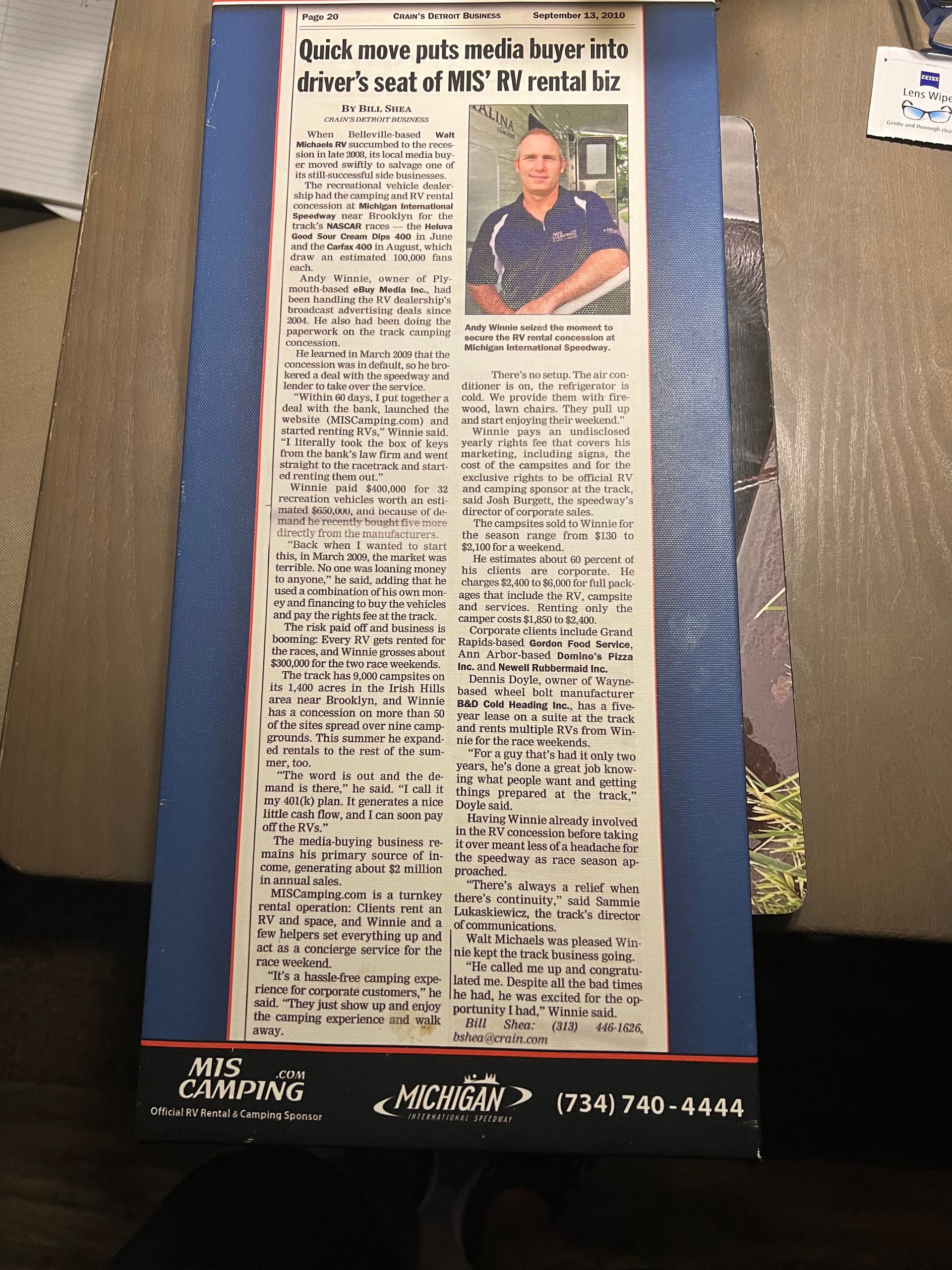 Newspaper article with photo of a man; blue border and company logo at the bottom.