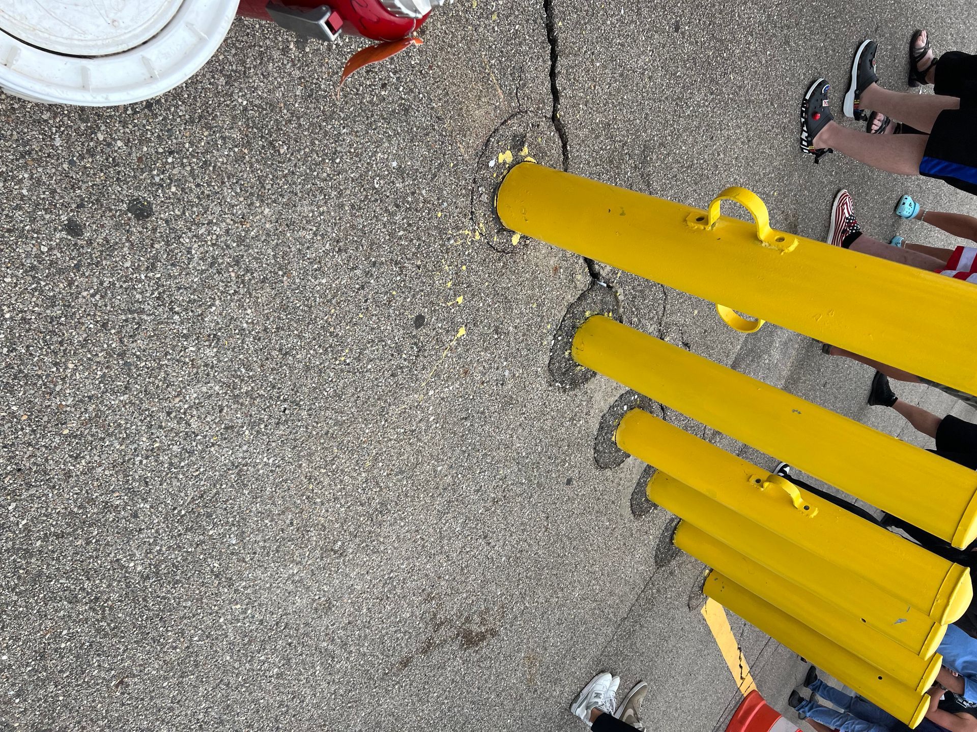 Yellow bollards on gray pavement with people nearby.