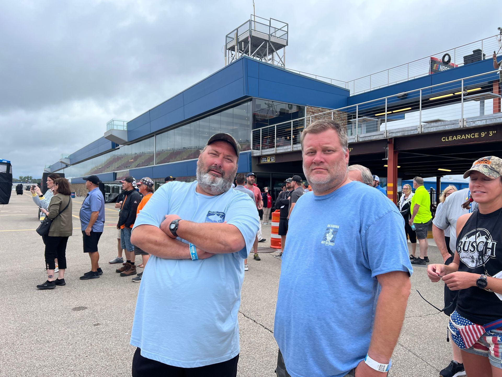 Two men smiling at a racetrack. 