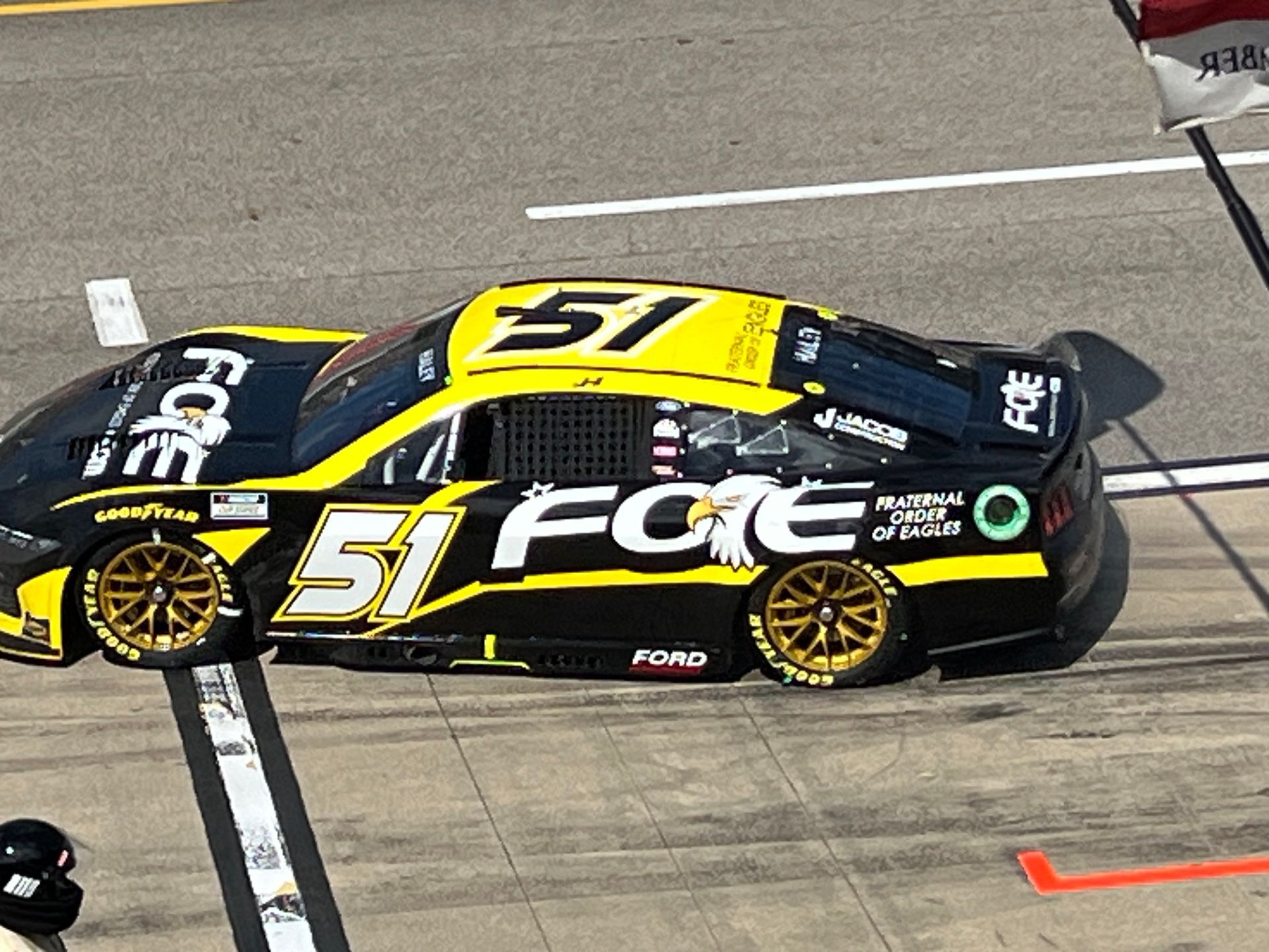 Black and yellow race car, number 51, at a pit stop. Ford branding visible.