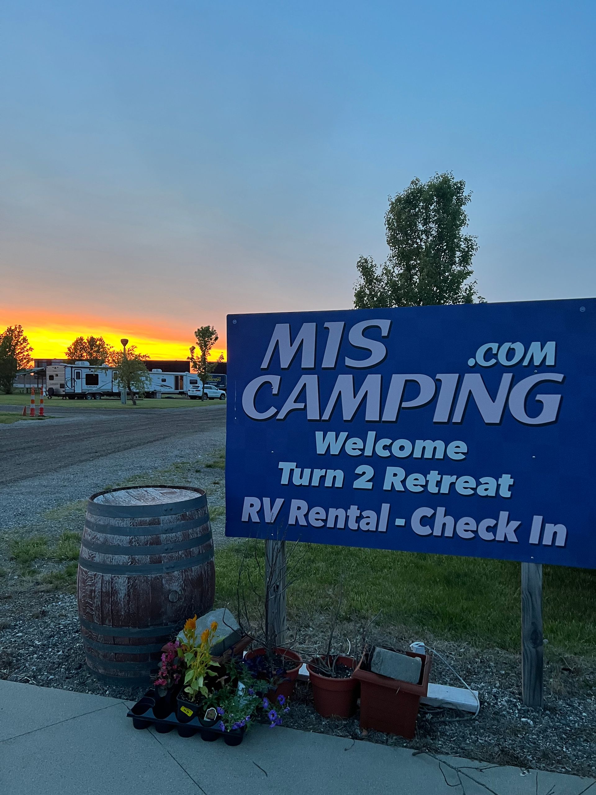 Blue sign for MIS Camping, RV rental, with a sunset in the background.