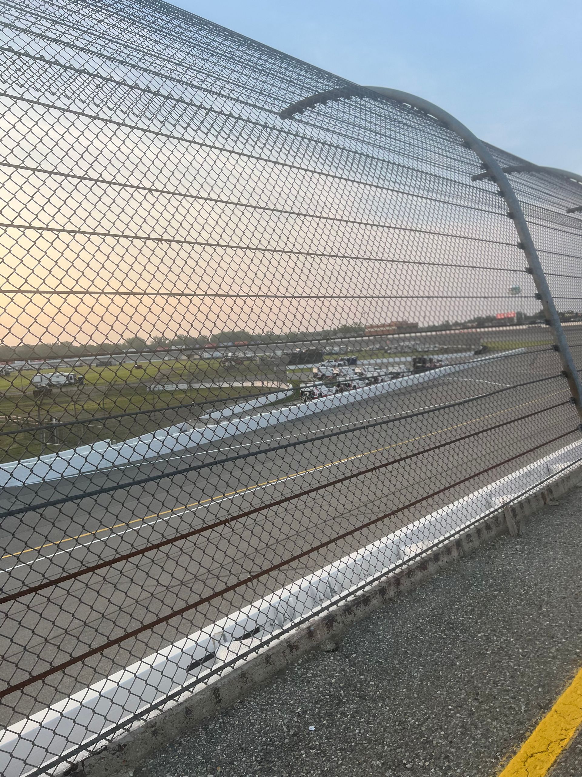 Highway with metal safety netting alongside, against a sky.