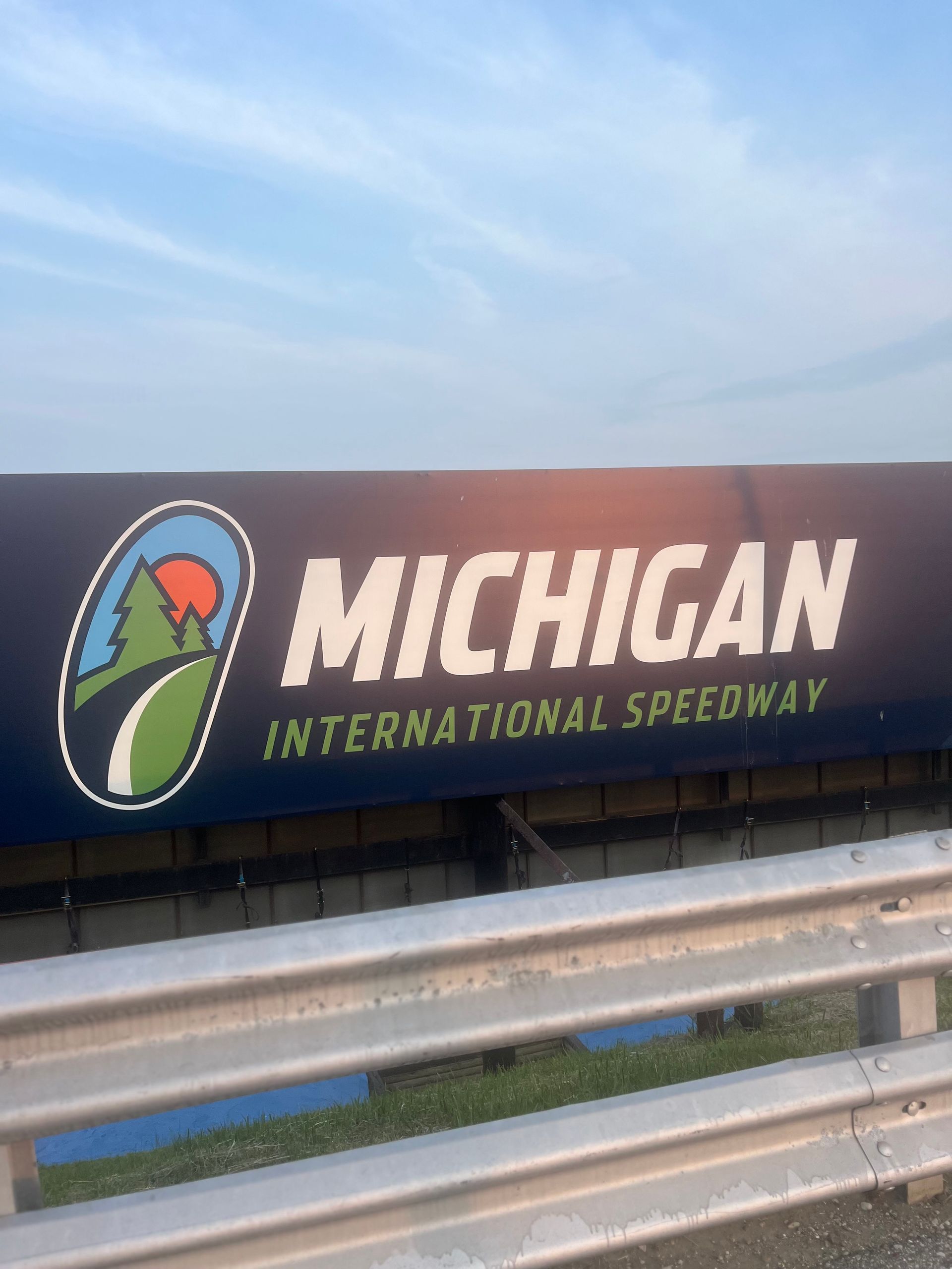 Sign for Michigan International Speedway with logo and sky background.