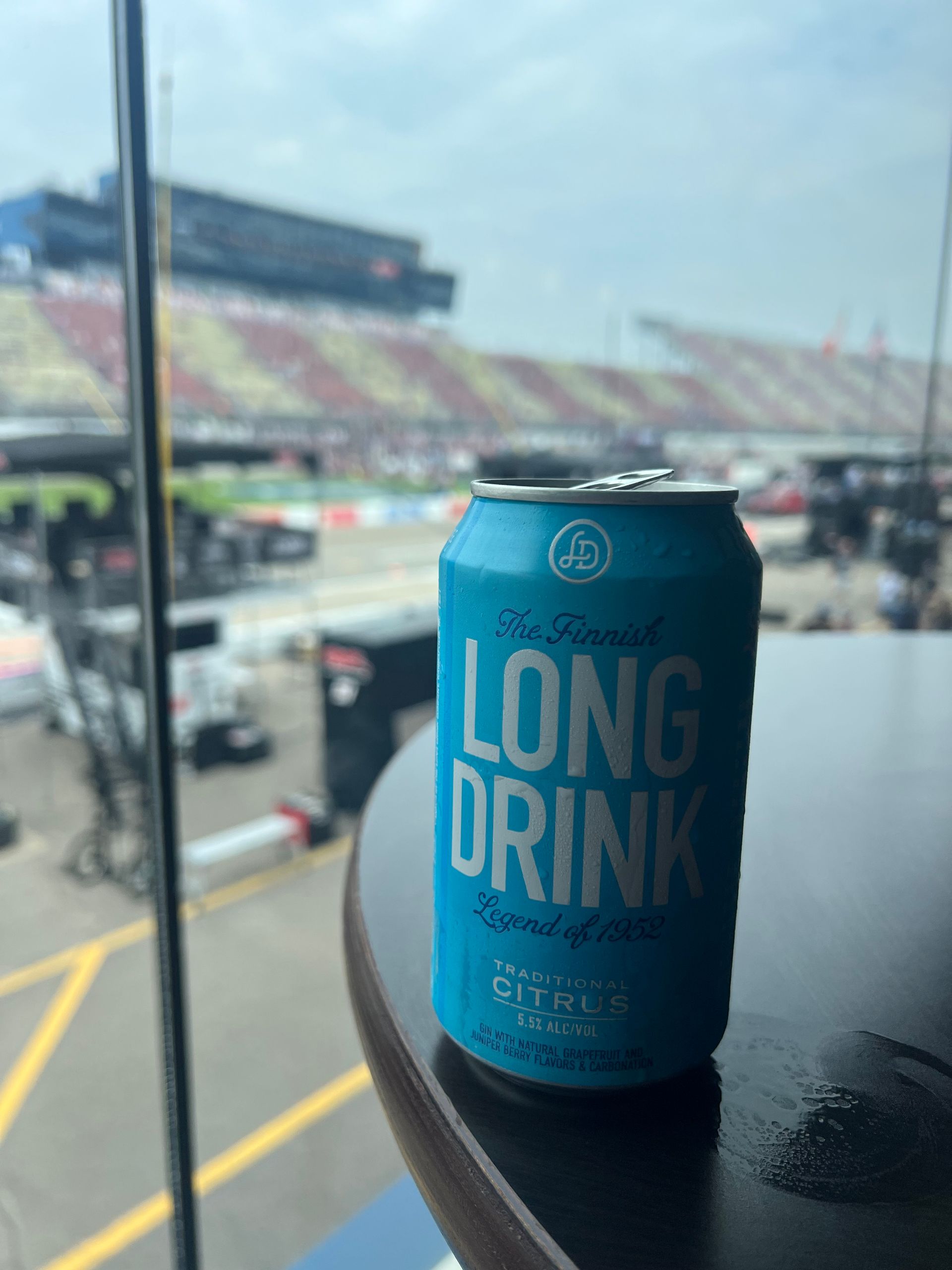 Blue Long Drink can on a table, with a racetrack in the background.