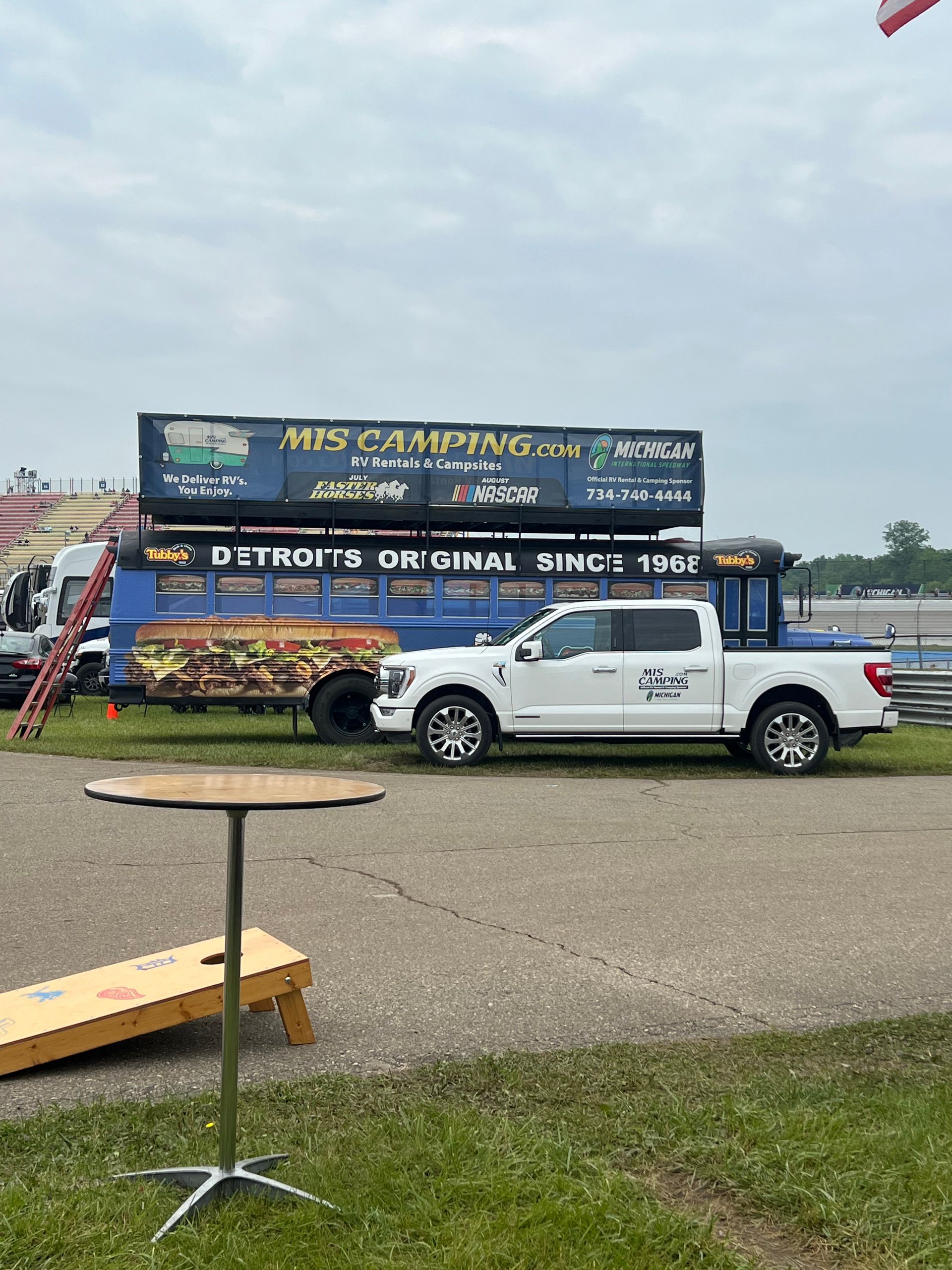 White pickup truck parked next to a food truck with a black awning that says 