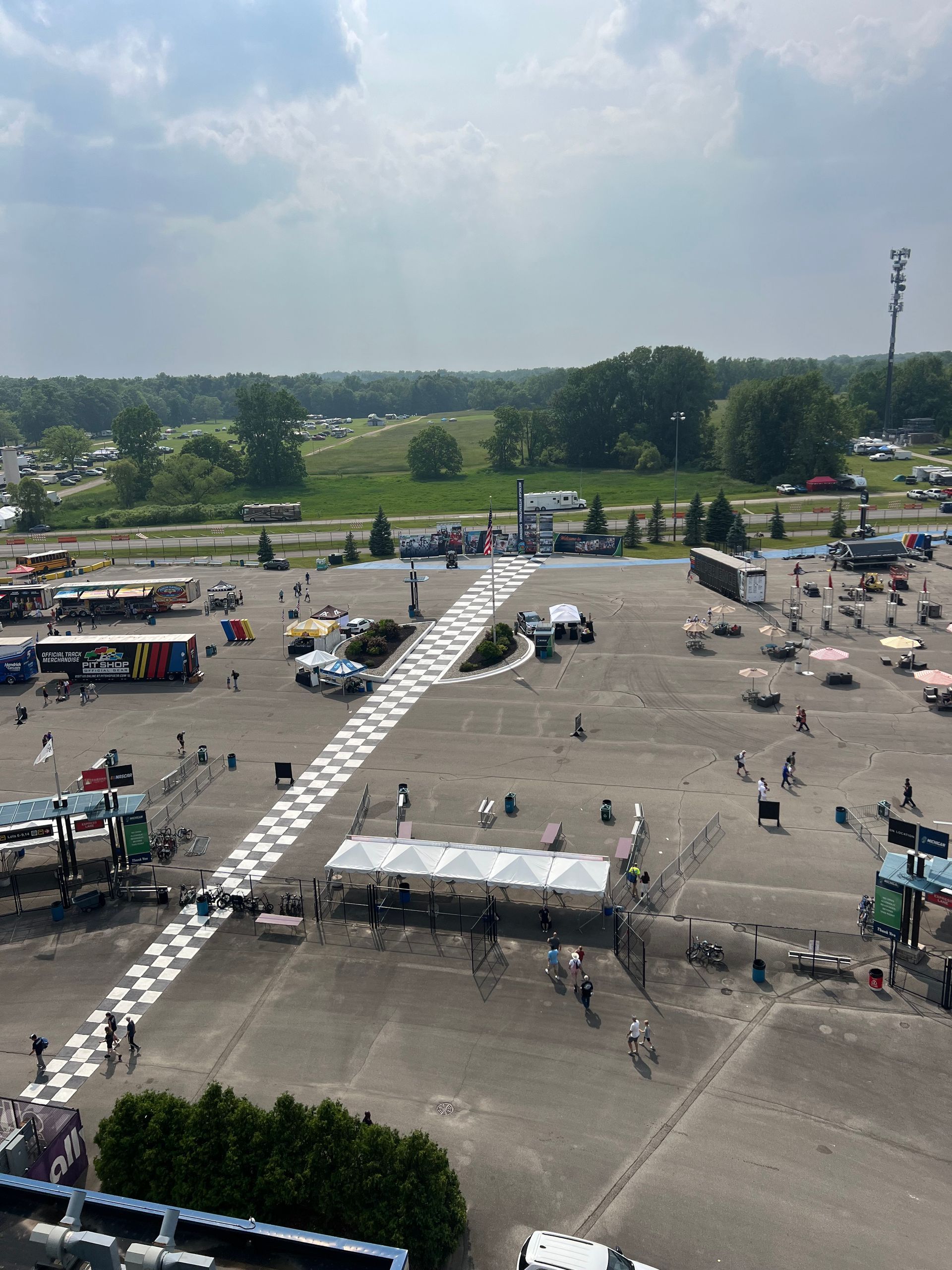Overhead view of a parking lot with race-related equipment. Checkerboard path leads to tents.
